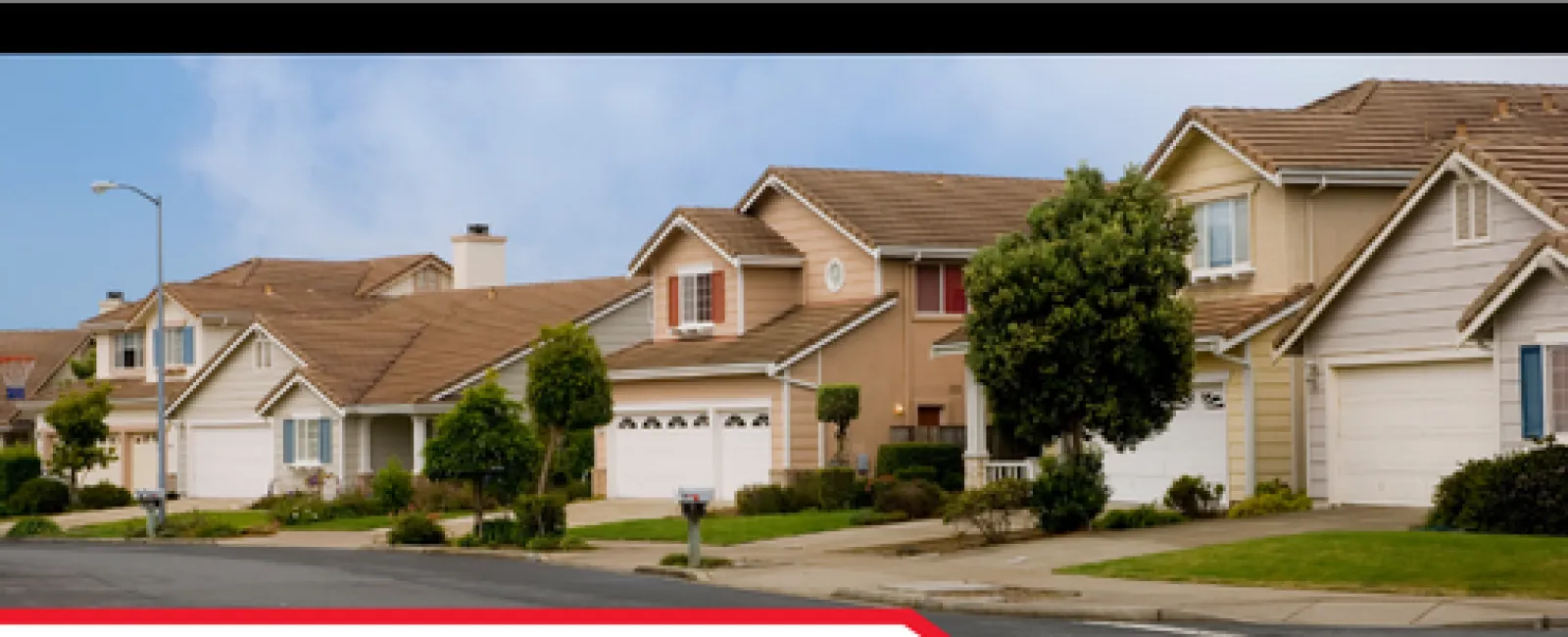 Row of suburban houses with garages and trees under a blue sky, highlighting home inspection challenges.
