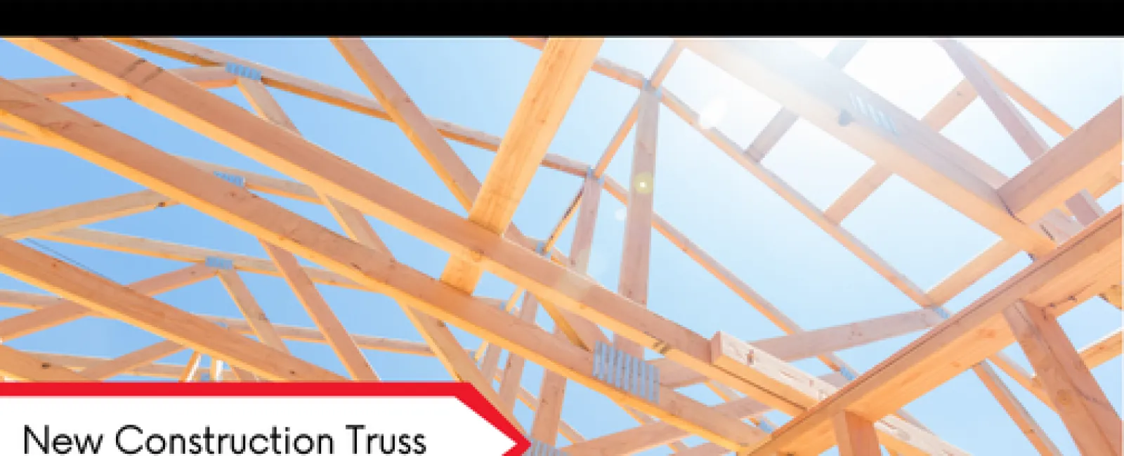 Wooden roof truss framing under clear blue sky for new residential construction project.