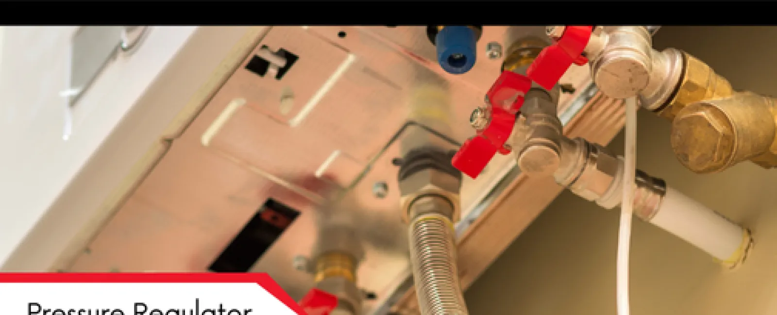 Close-up of a pressure regulator and connected pipes with red-handled valves in an industrial setting.