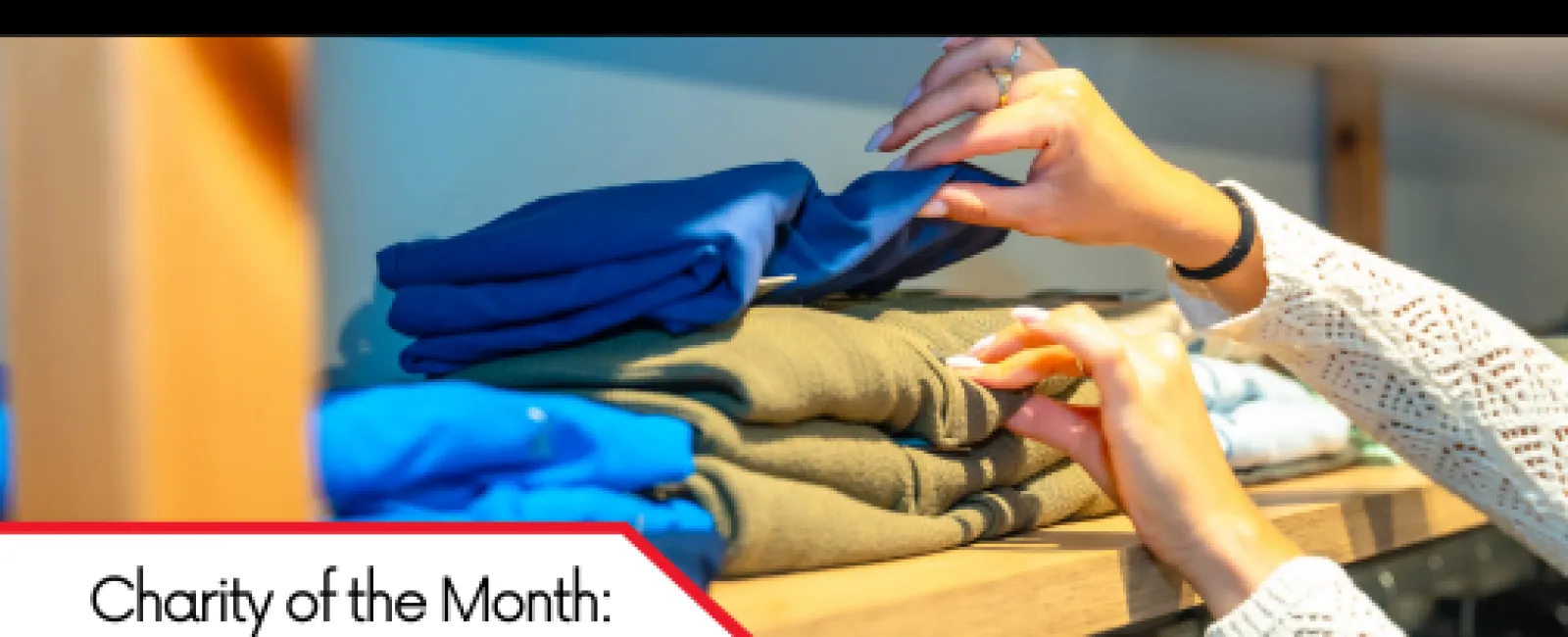 Hands organizing folded clothes on a wooden shelf promoting January 2022 charity of the month for LunsPro Inspections.