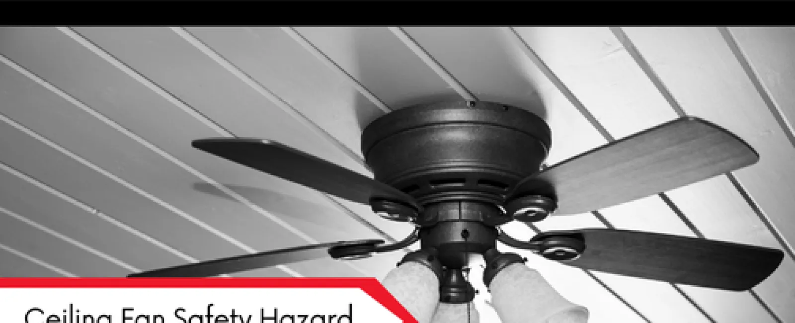 Black ceiling fan with lights mounted on a slanted wooden ceiling highlighting a safety hazard.