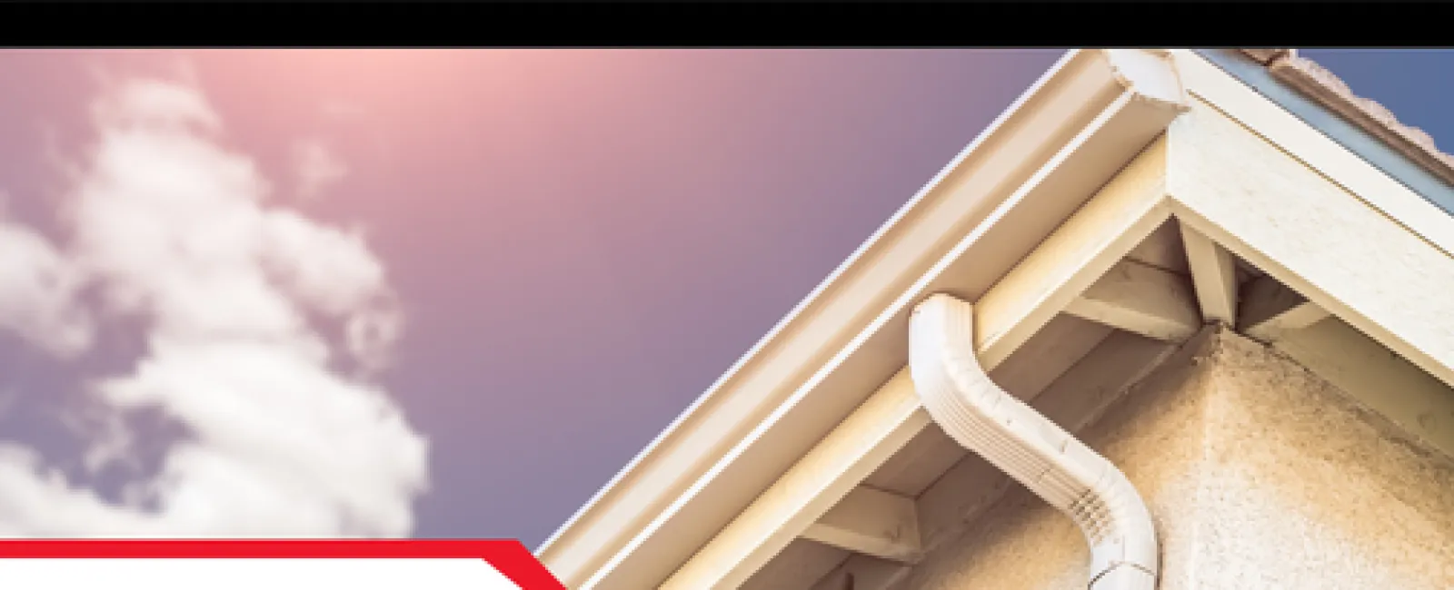 White downspout drain attached to a house gutter under clear sky with clouds and sunlight.