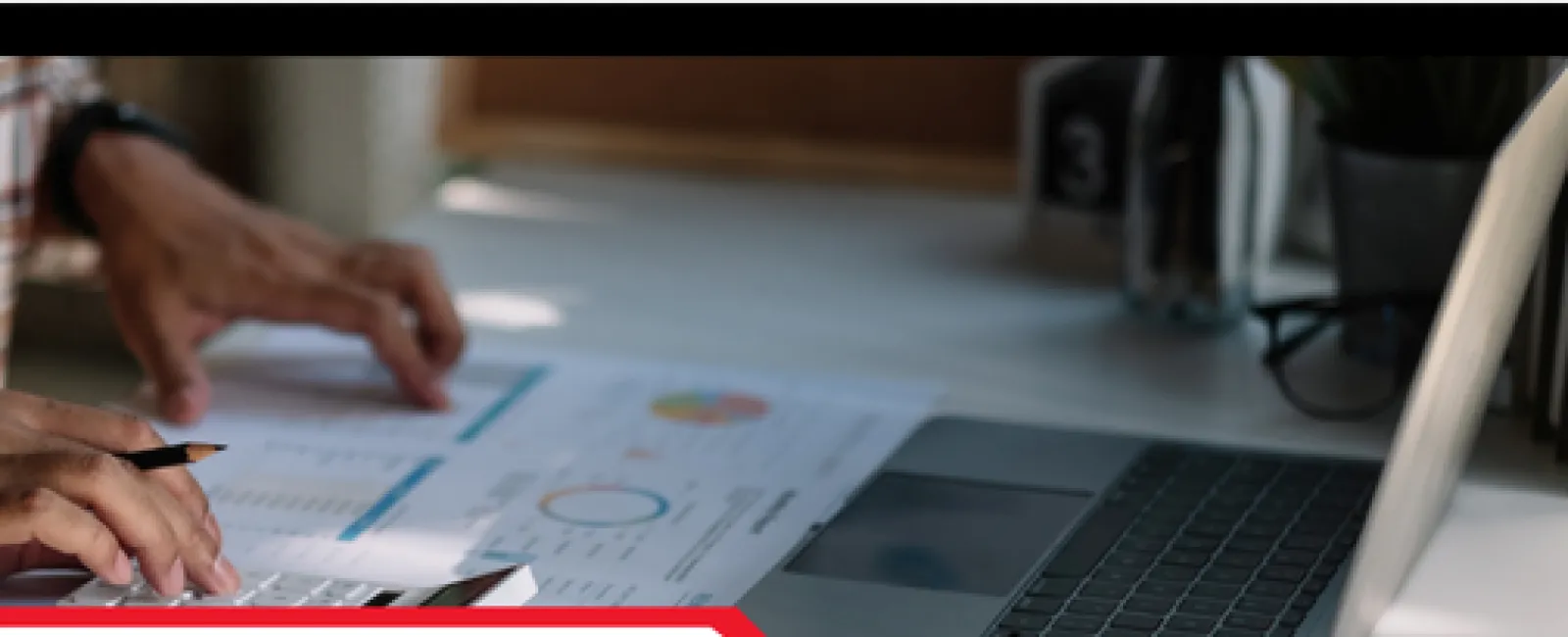 Person using calculator and reviewing printed inspection report charts next to an open laptop on a desk.