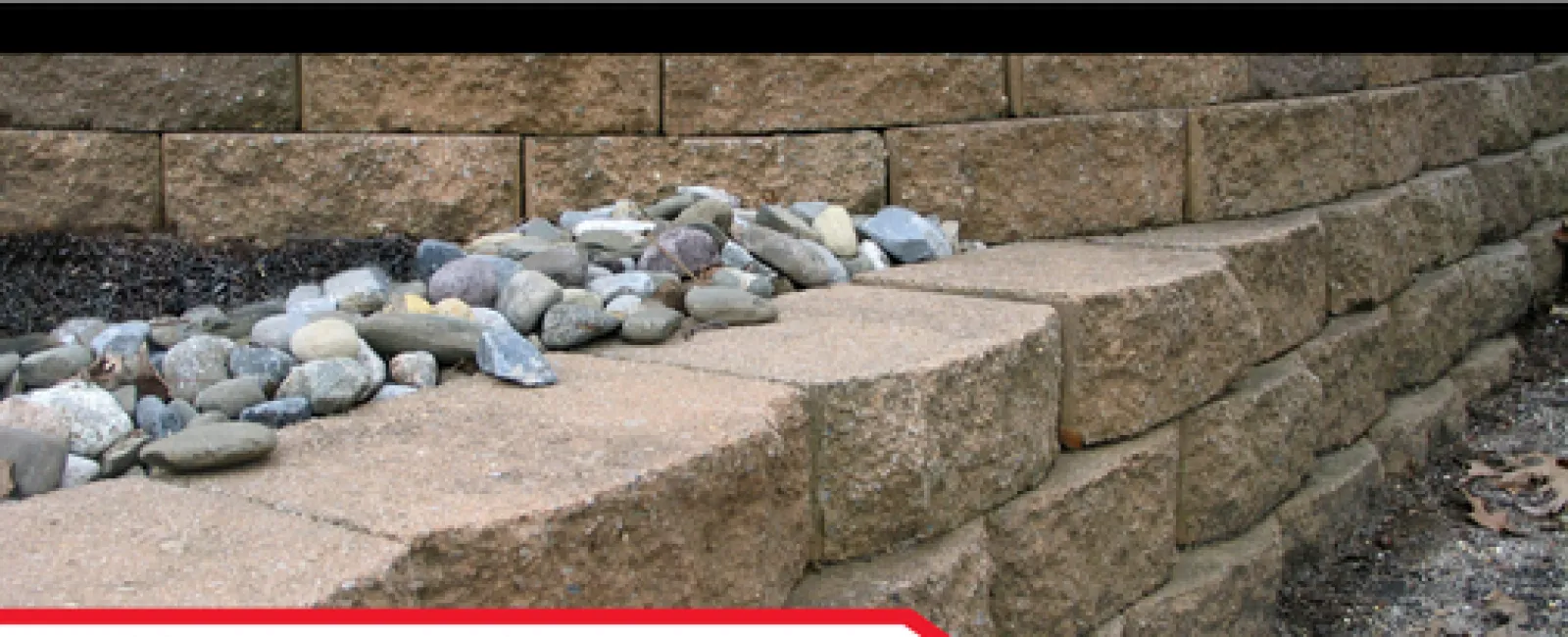 Close-up of a stone retaining wall with small rocks, emphasizing home inspection importance and safety hazards.
