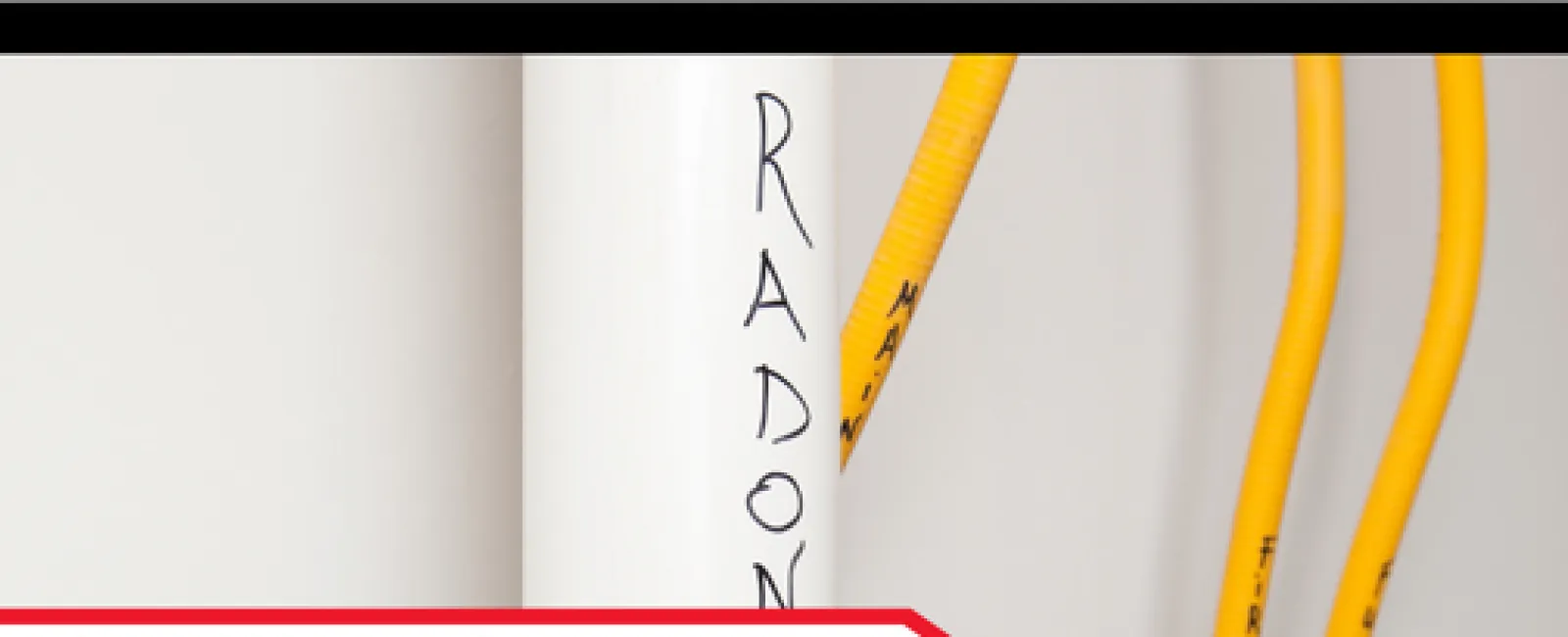 Close-up of radon mitigation system pipes with 'Radon' label and yellow electrical cables indoors.