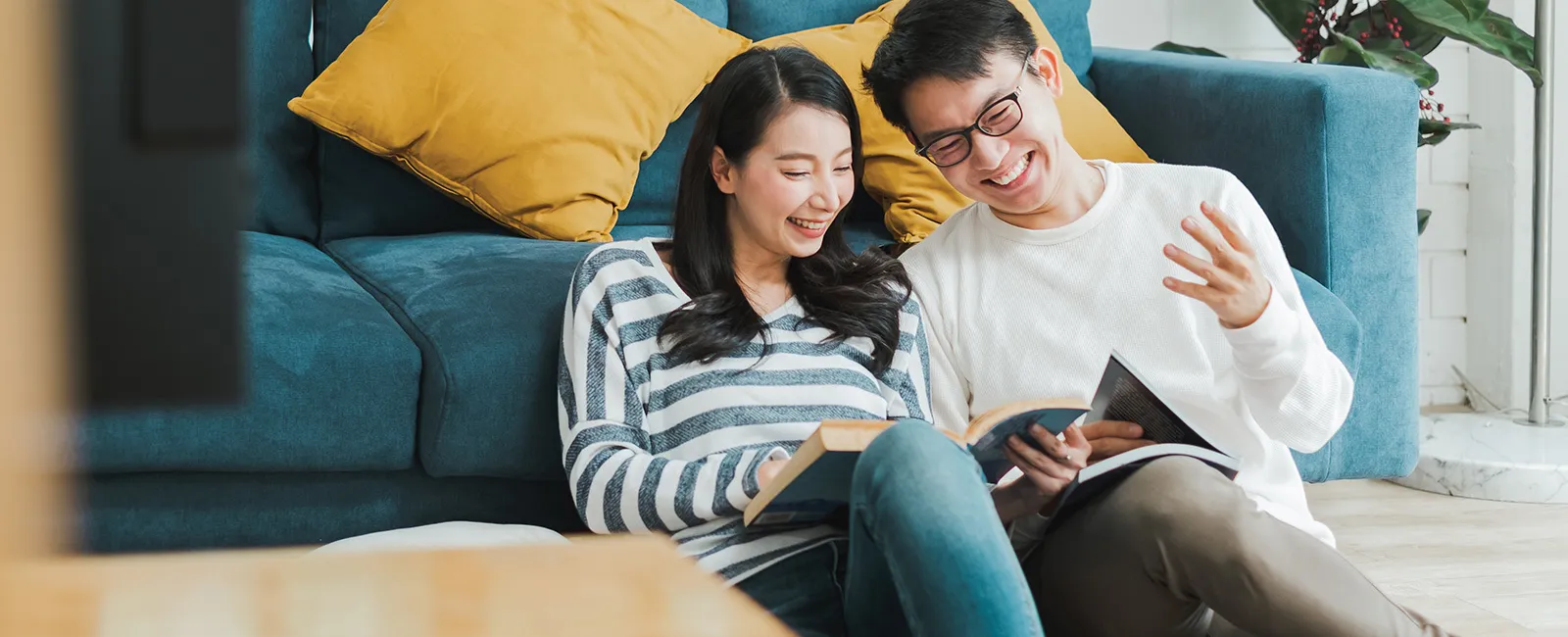 a man and a woman sitting on a couch looking at a book