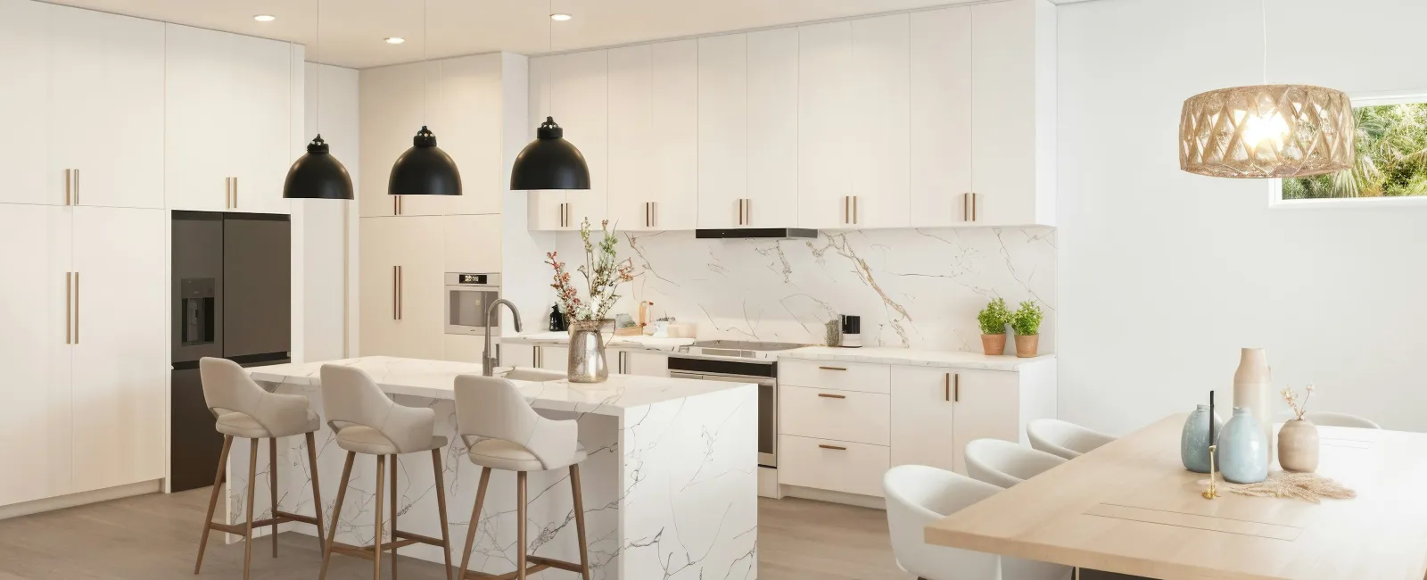 Bright modern kitchen with white cabinetry, marble island, black pendant lights, and a wooden dining table with white chairs.