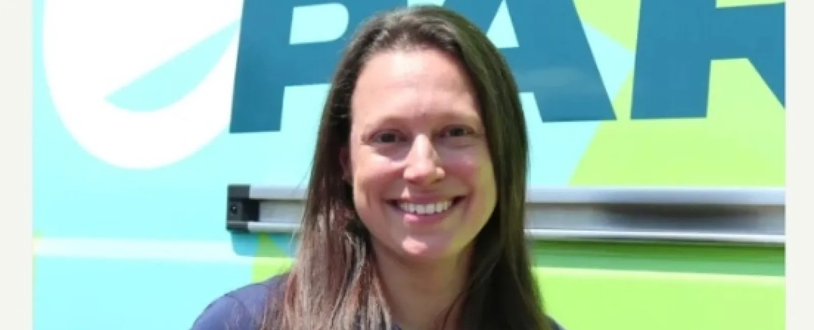 Portrait of Lizzie Sigafoos, standout female franchise owner, smiling in front of branded background.