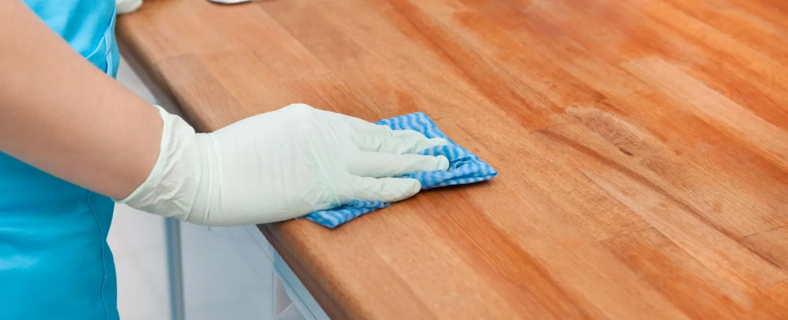 a person's hand with gloves on a wooden table