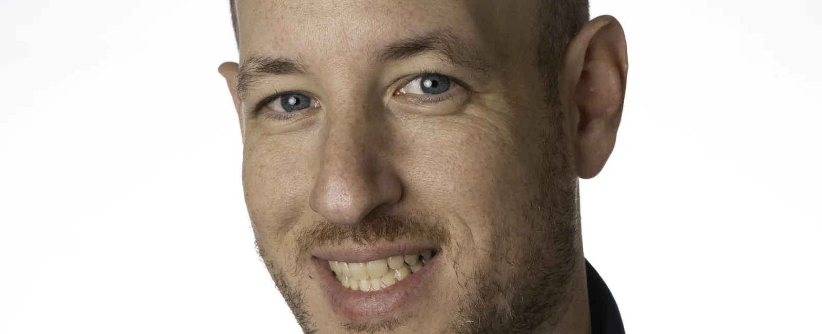 Smiling man wearing a navy blue MaidPro polo shirt with logo on a white background in a studio portrait.