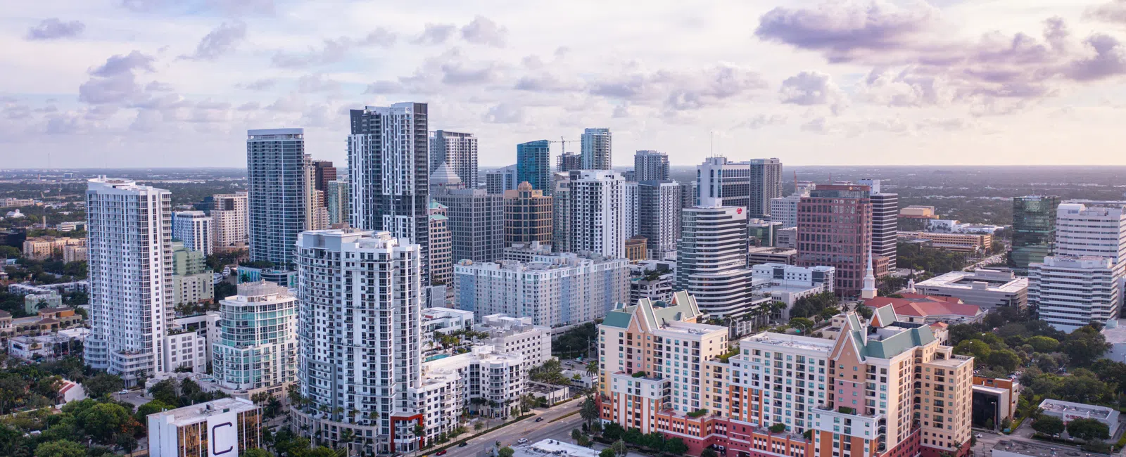 Aerial view of a modern city skyline with high-rise buildings under a cloudy sky at dusk.