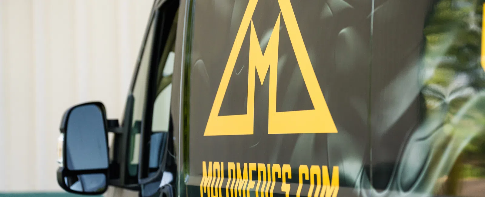 Close-up of a black van with yellow MoldMedics.com logo and website address on its side.