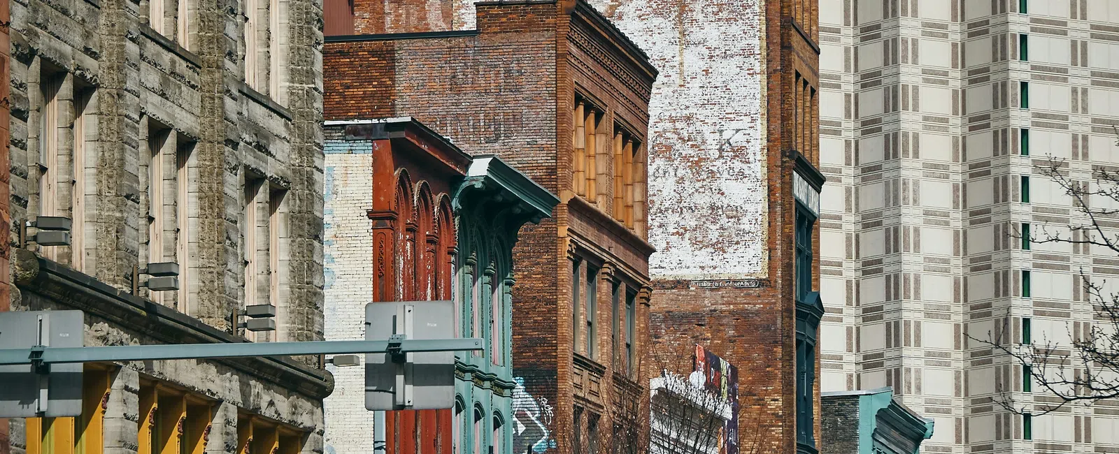 Urban streetscape with historic brick buildings and modern high-rises in the background under clear skies.