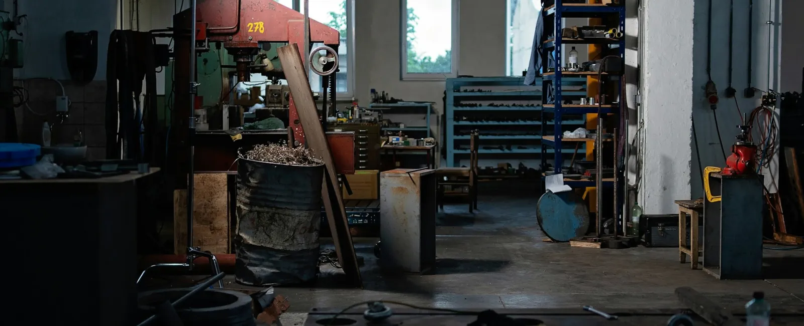 An industrial workshop with machinery, tools, and storage shelves bathed in soft lighting.