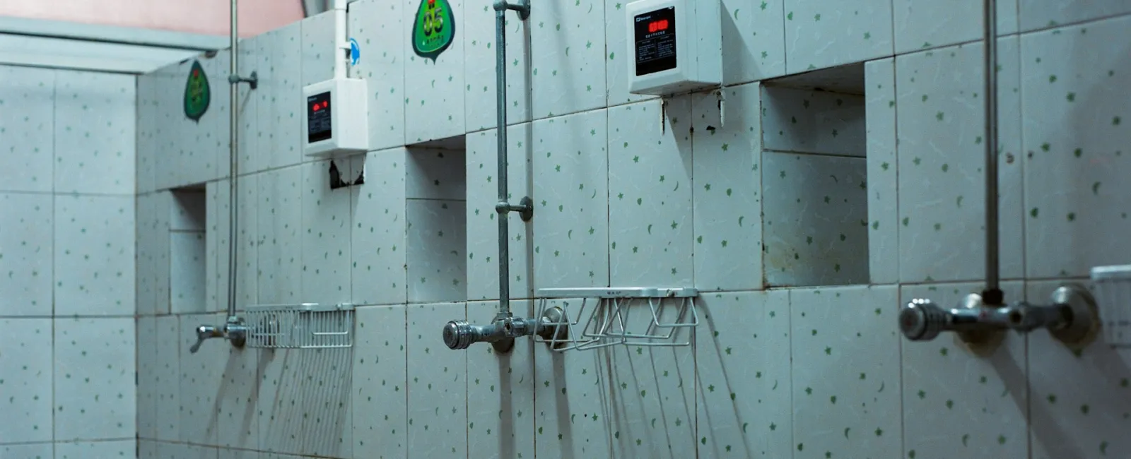 Interior view of a minimalist public shower area with tiled walls and multiple shower heads.