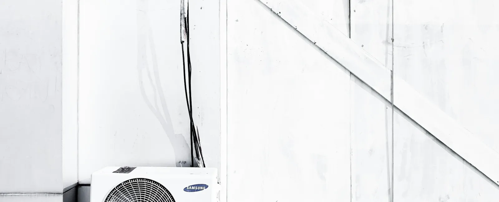 A compact air conditioning unit against a minimalist wall background.