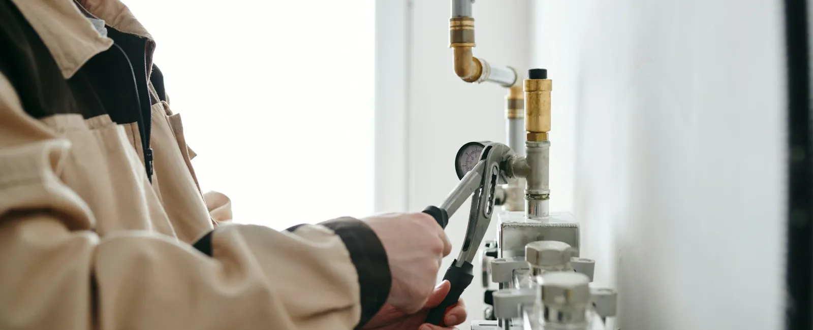 A plumber uses adjustable pliers on a pipe fitting in a modern setting.