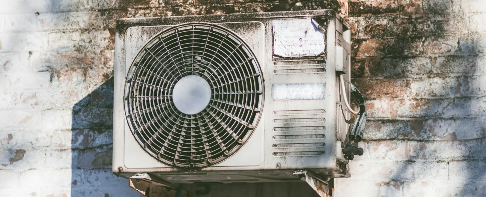 An old air conditioning unit mounted on a weathered wall with visible dirt and wear.