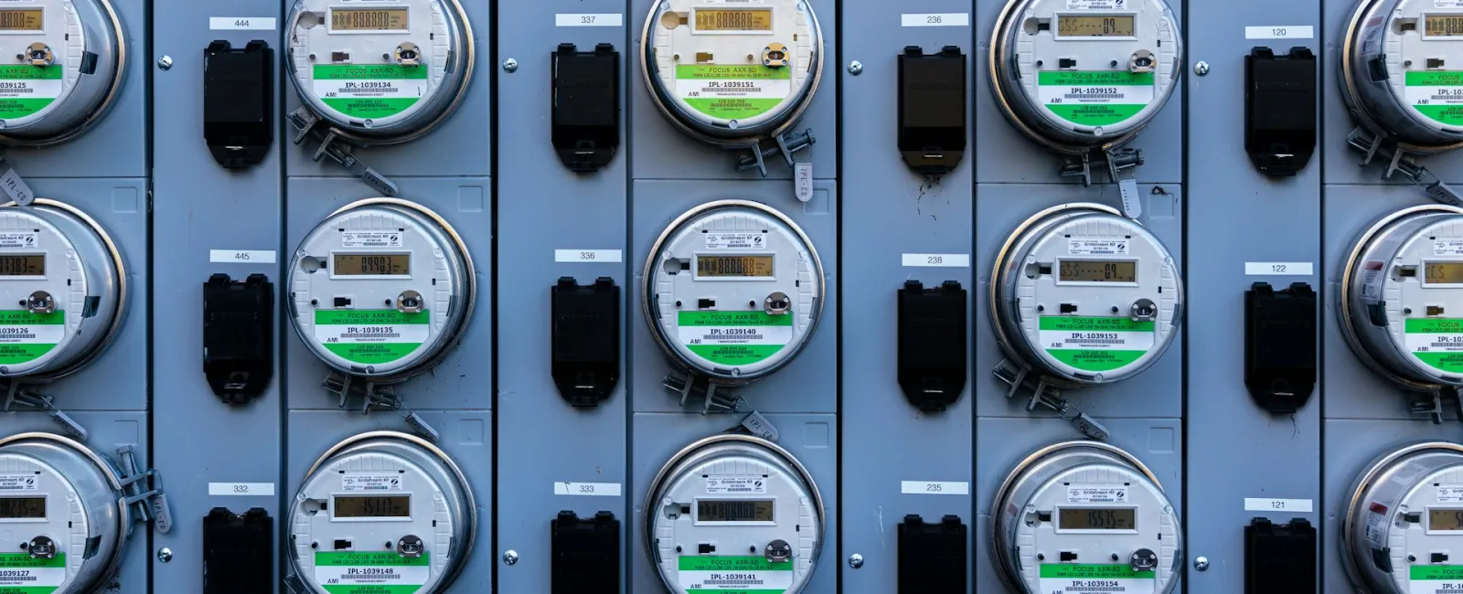 Close-up of multiple electric meters lined up on a wall, showcasing their detailed displays and labels.