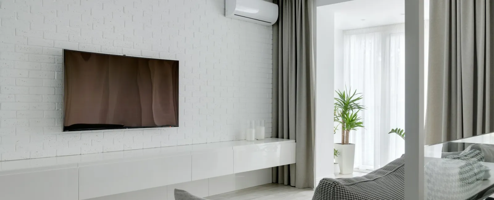 Modern living room featuring a minimalist design with a wall-mounted TV and large windows.