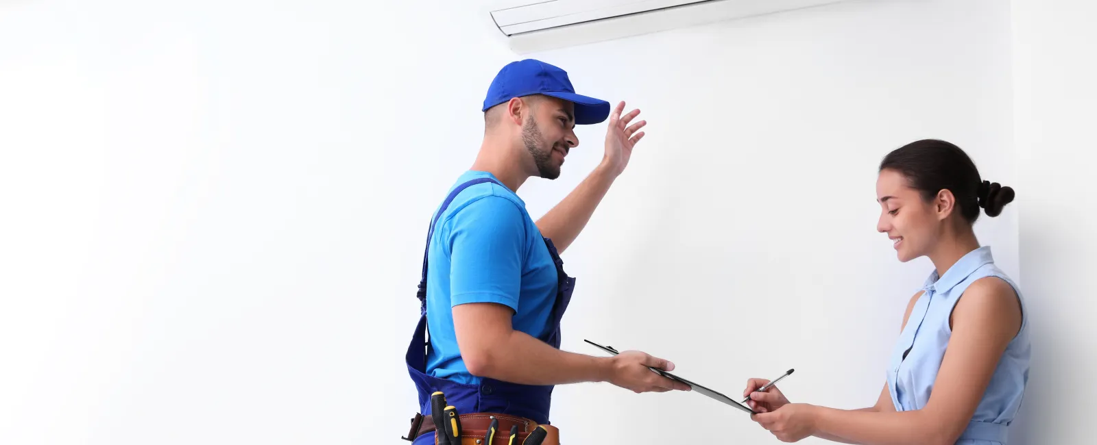 Air conditioning technician explaining service to a customer in a modern home setting.