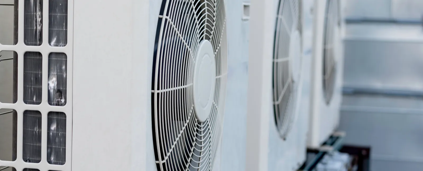 Close-up of outdoor air conditioning units with visible fans and metal casing.