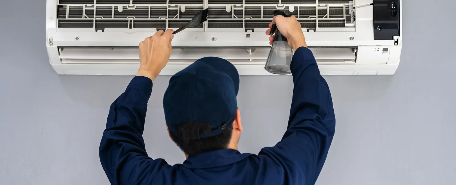Technician cleaning an air conditioner unit for maintenance and efficiency.