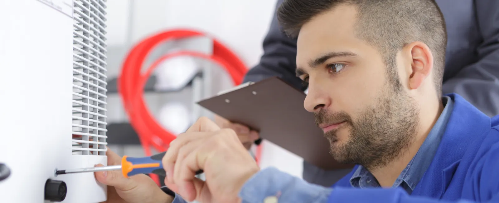 Technician repairing equipment with a screwdriver in a workshop environment, focused and attentive to details.