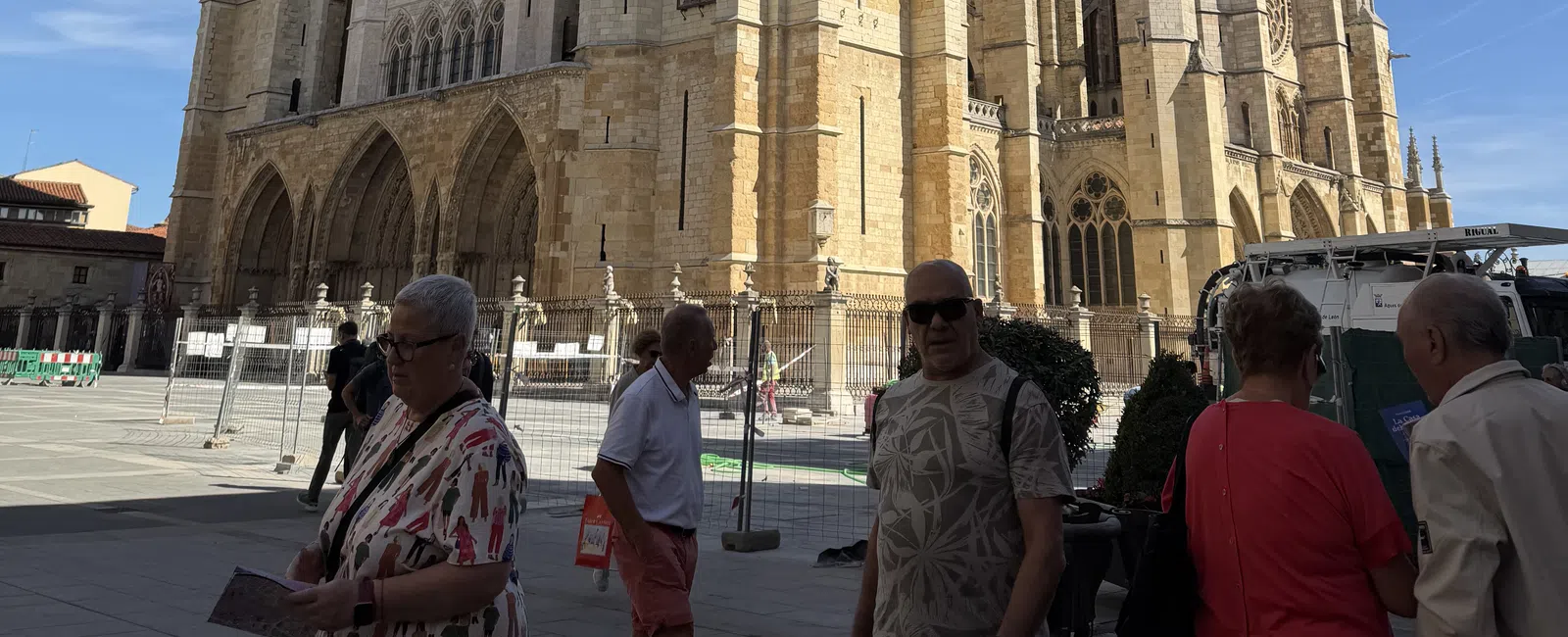 Large Gothic-style cathedral with intricate architecture under a clear blue sky and people walking in front.