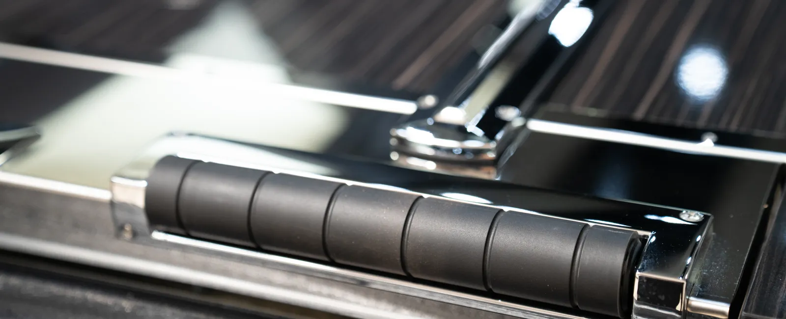 Close-up view of a sleek, modern black and chrome handle on a luxury vehicle door with textured details