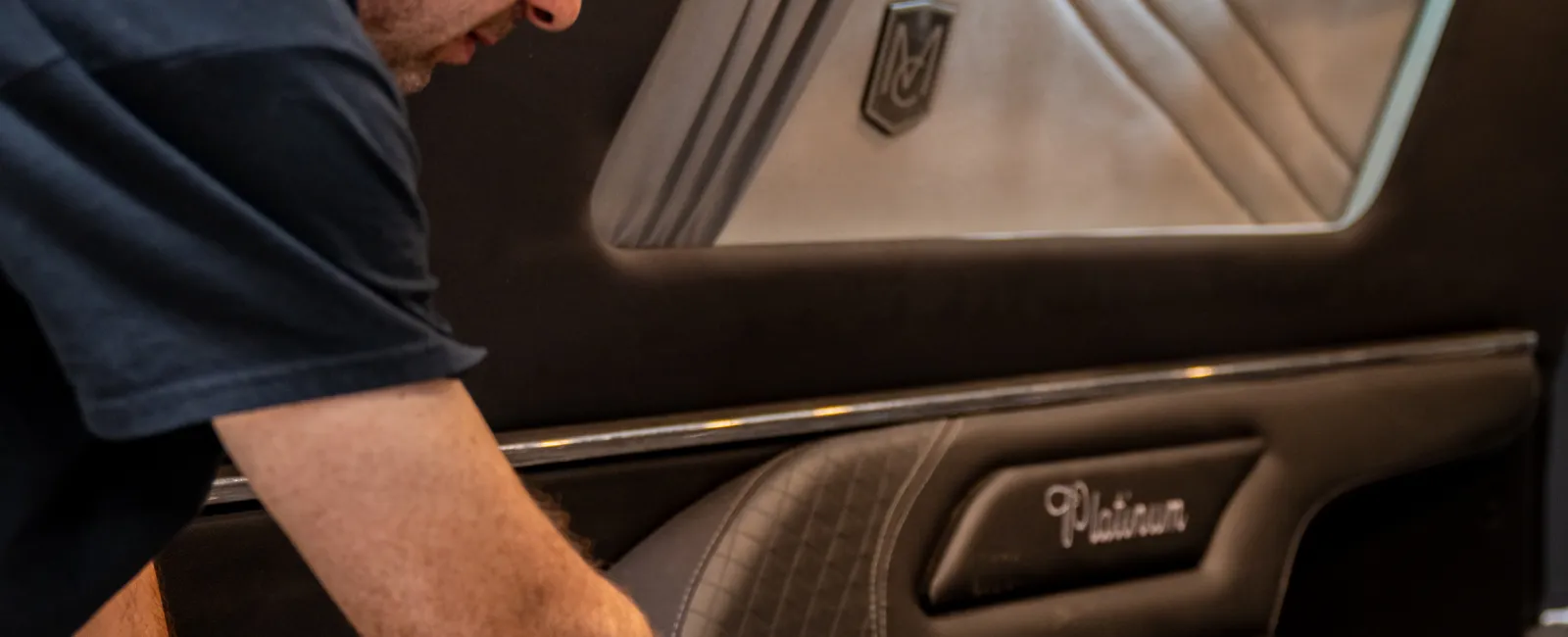 Man working on installing or customizing an upholstered vehicle interior panel with detailed stitching and markings.
