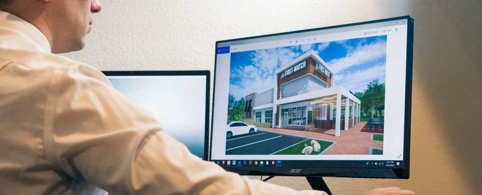 Architect reviewing a 3D building design of First Watch restaurant on a computer monitor in an office.