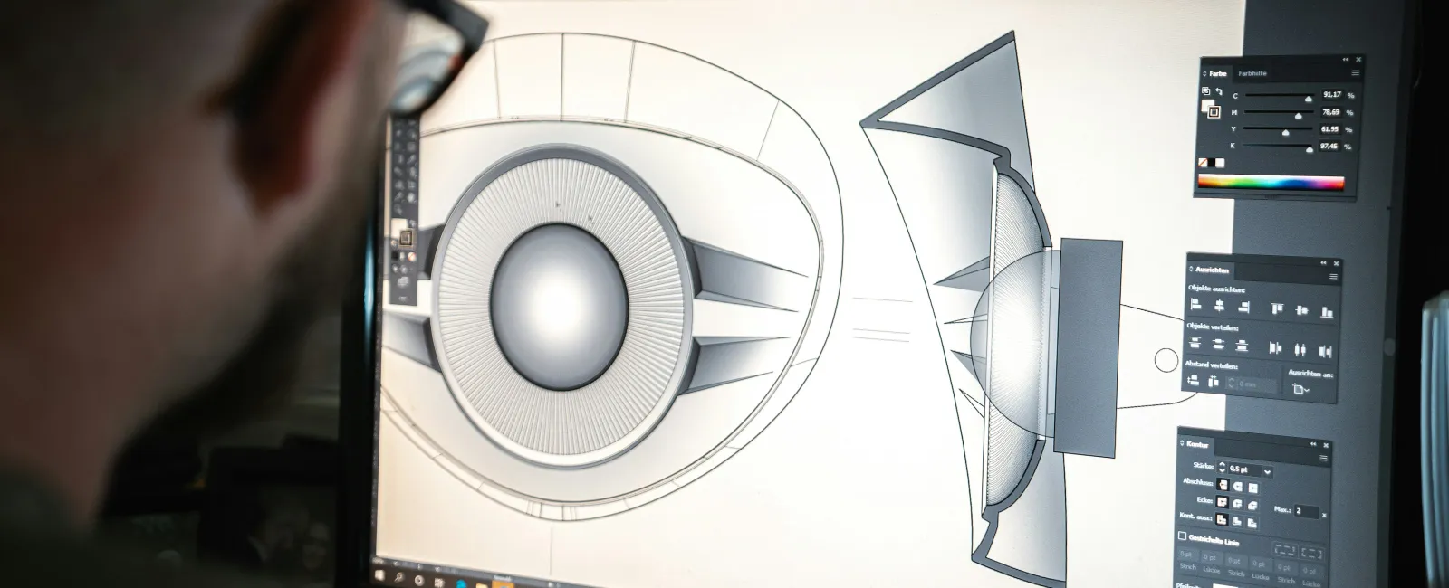 Designer working on 3D model of an eye with CAD software on a computer screen in a dark room.