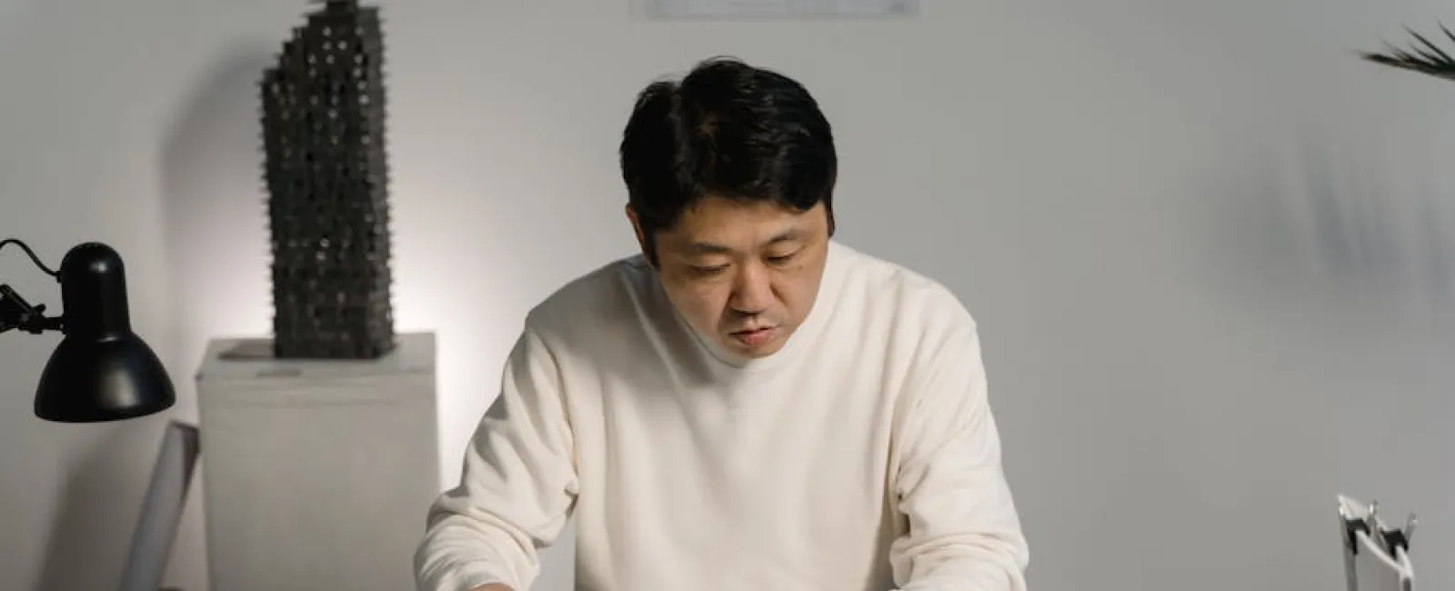 Architect studying a white architectural model and blueprints in a modern office workspace