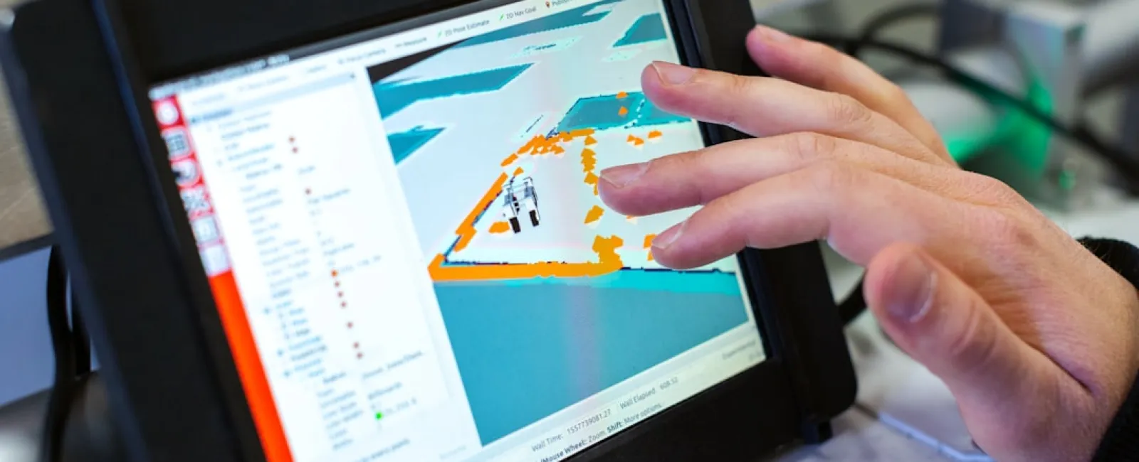 Hand interacting with a tablet displaying a 3D mapping software interface with highlighted areas in orange