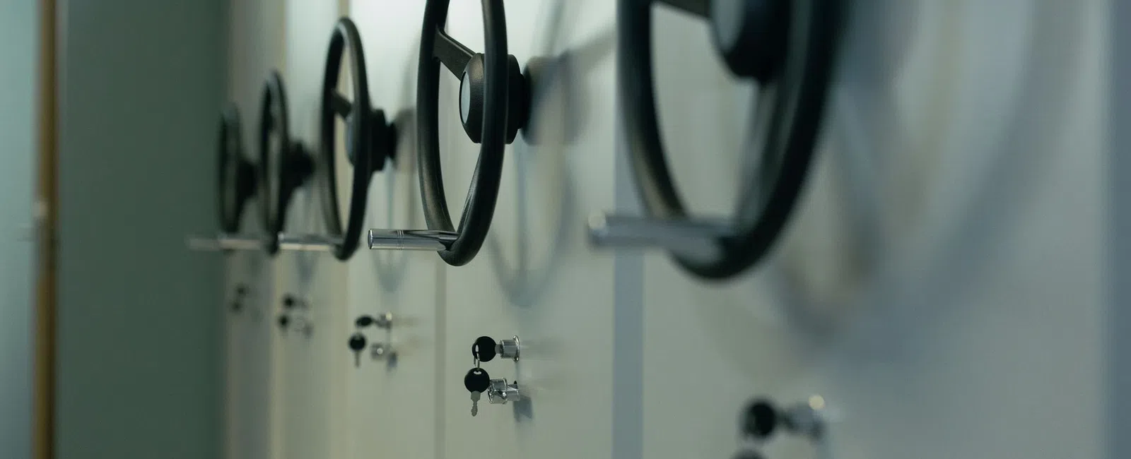 Close-up of multiple black handwheels on white storage cabinets with key locks in a row.