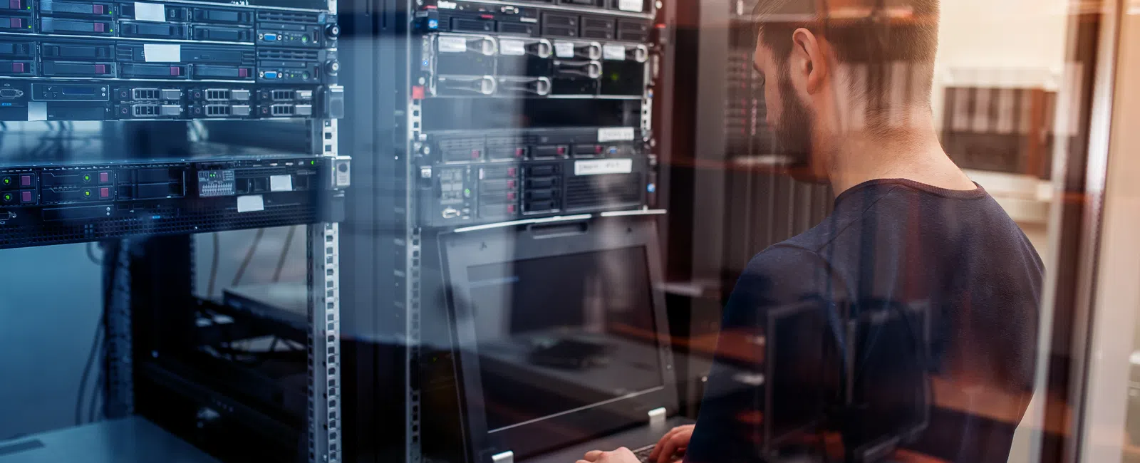 IT professional managing servers in a data center using a laptop in a secure server room environment