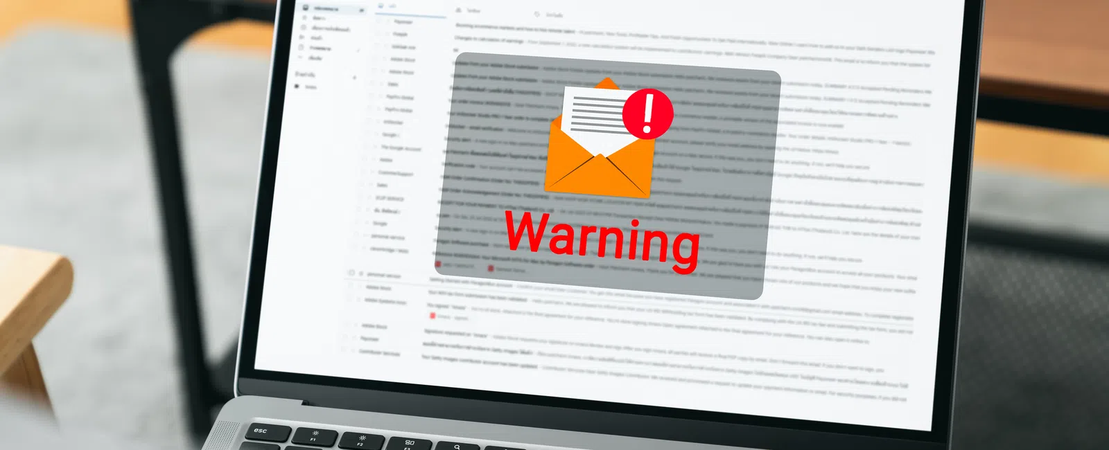 Laptop screen showing email interface with a red warning sign on an envelope icon for email alert.