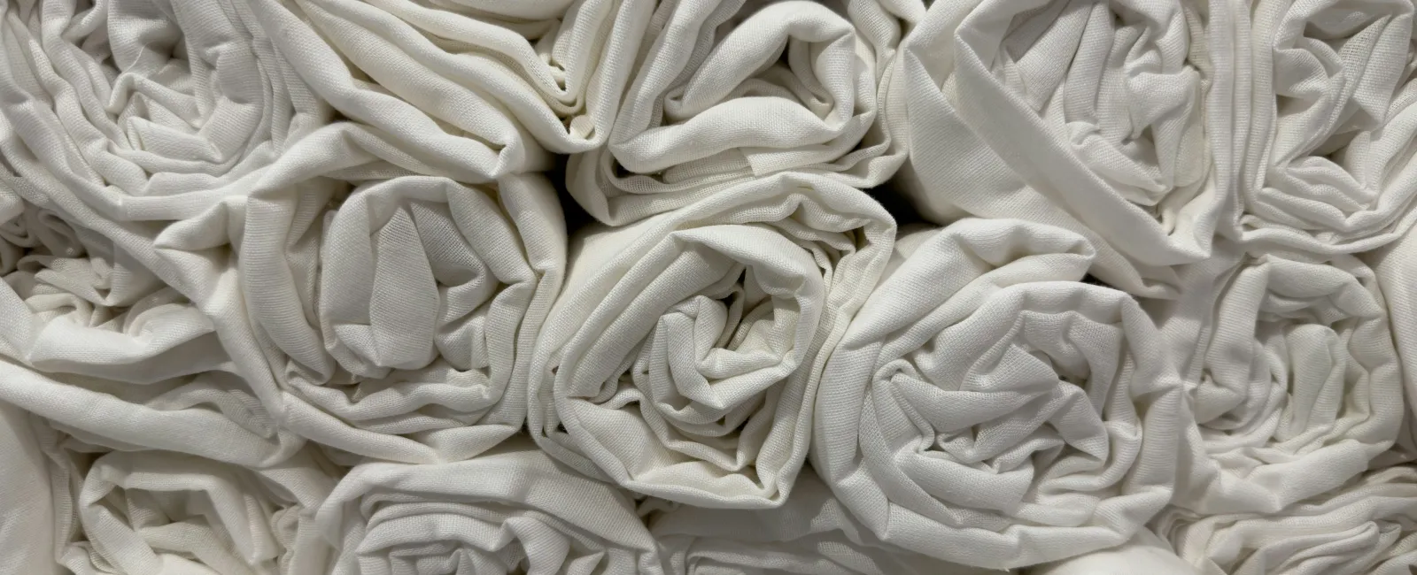 Close-up of neatly rolled white fabric pieces stacked together in a grid pattern.