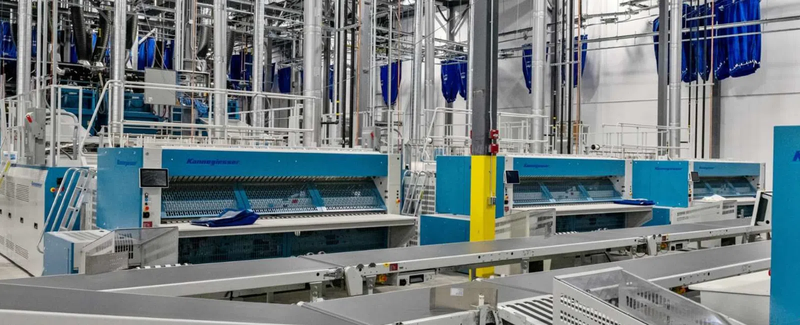 Modern industrial laundry facility with automated large-scale washing machines and conveyor systems