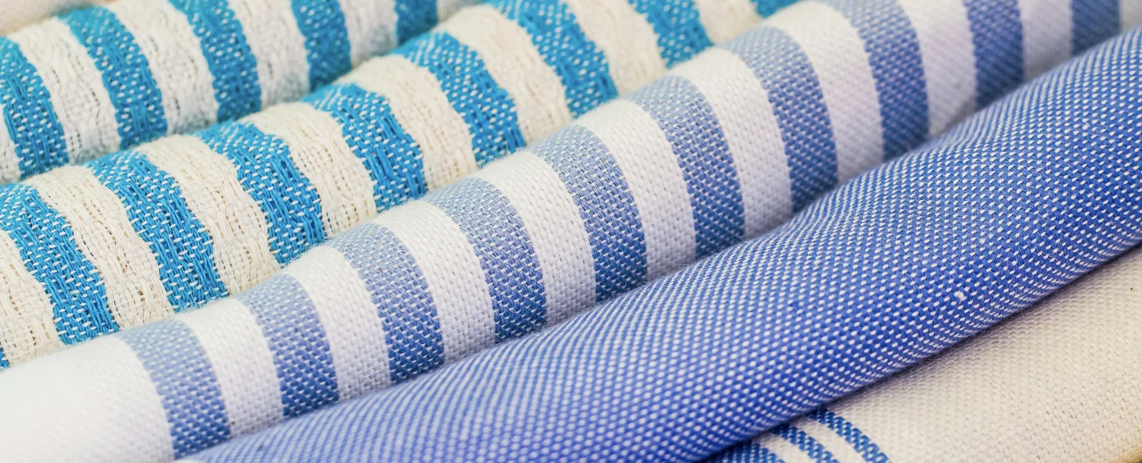 Close-up of rolled blue and white striped fabric patterns with various textures and shades.