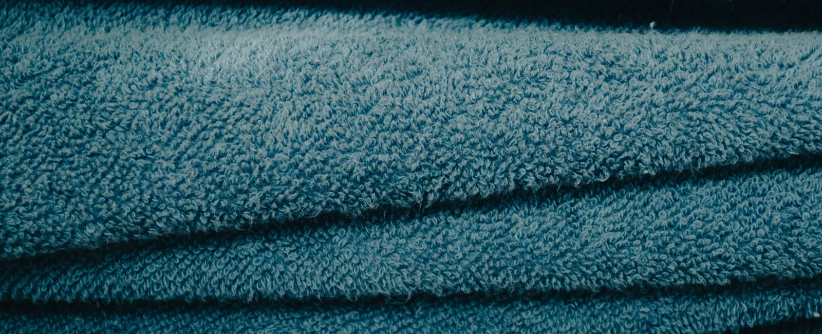 Close-up of folded blue textured towels stacked neatly in a pile.