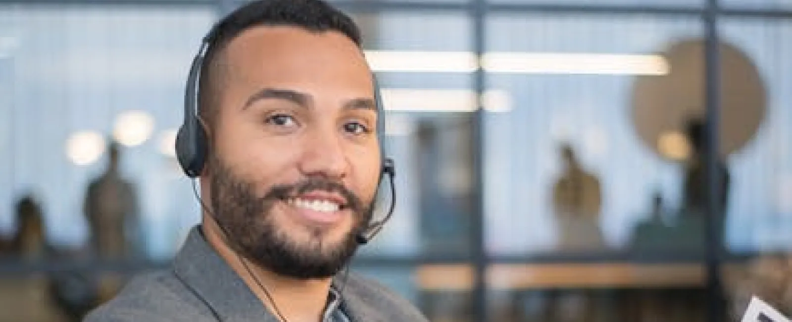 Smiling customer service representative wearing headset holding document in modern office setting