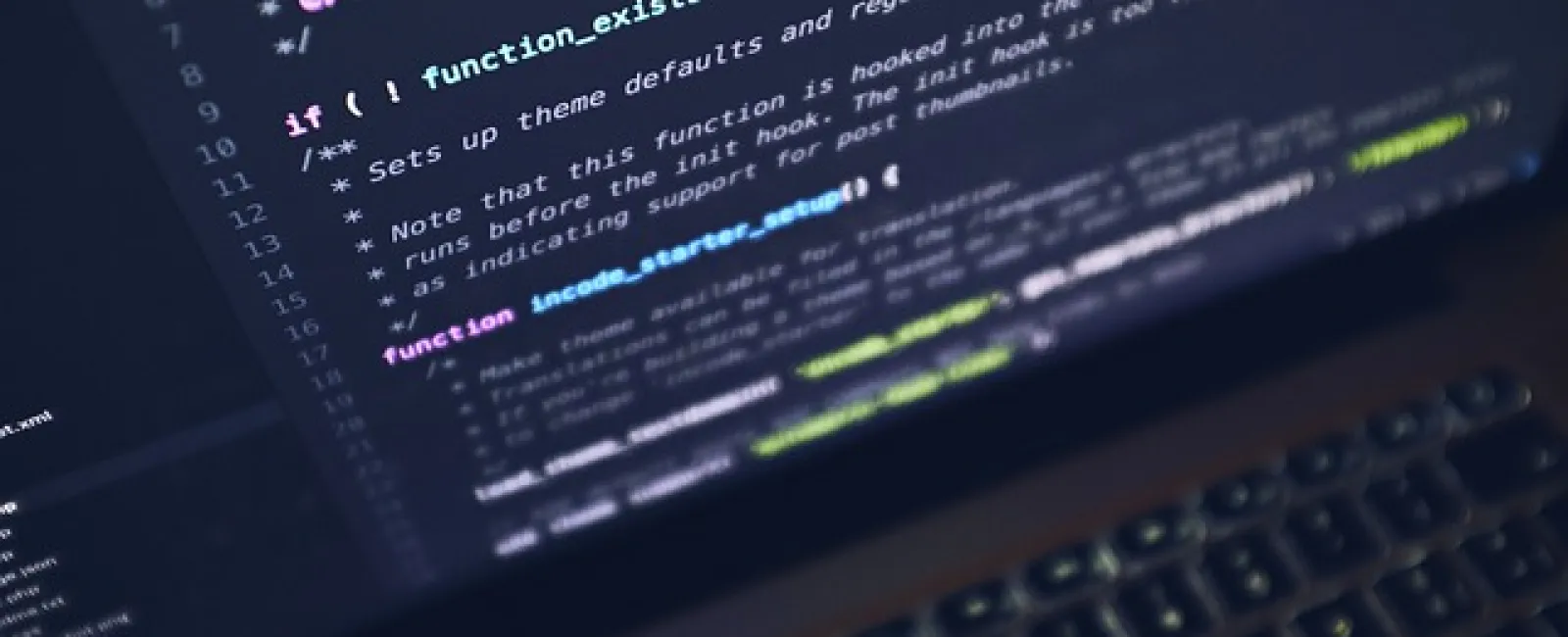 Close-up of laptop screen displaying coding script with colorful syntax and blurred keyboard in background