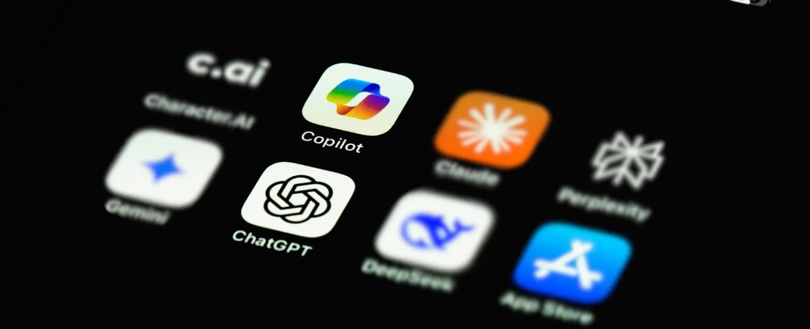 Close-up of smartphone screen showing AI app icons including ChatGPT vs Copilot.
