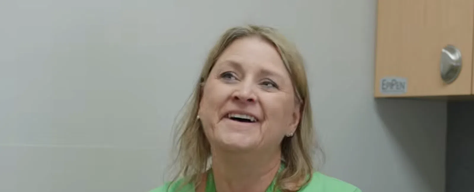 Smiling woman in a green shirt and OrthoSouth lanyard talking in an office setting