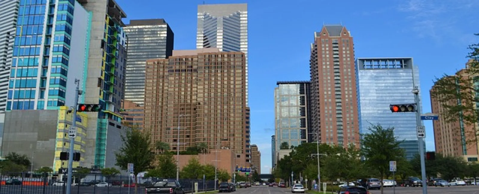 City street view with modern high-rise buildings under a clear blue sky during daytime.