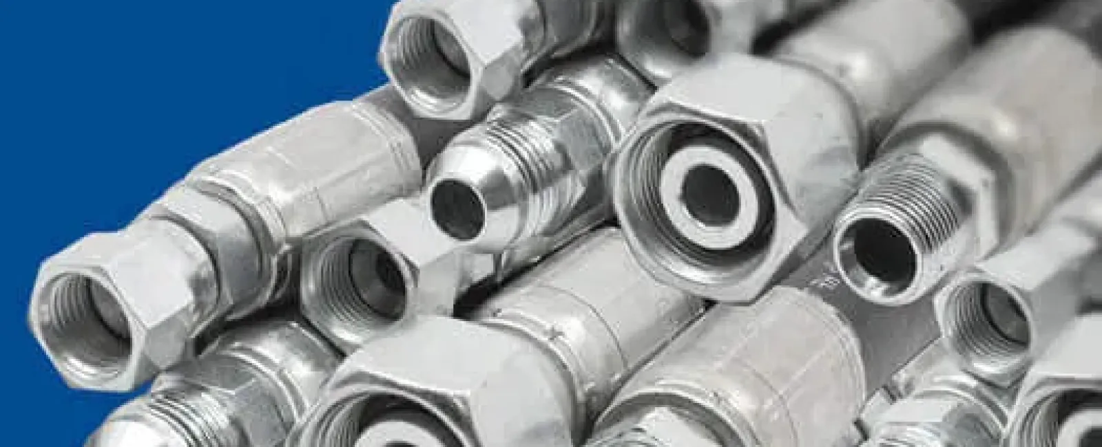 Close-up of multiple industrial metal hydraulic hoses with threaded connectors on a blue background