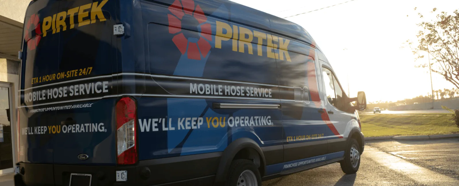 Blue Pirtek mobile hose service van parked outside during sunset with company branding and service details.