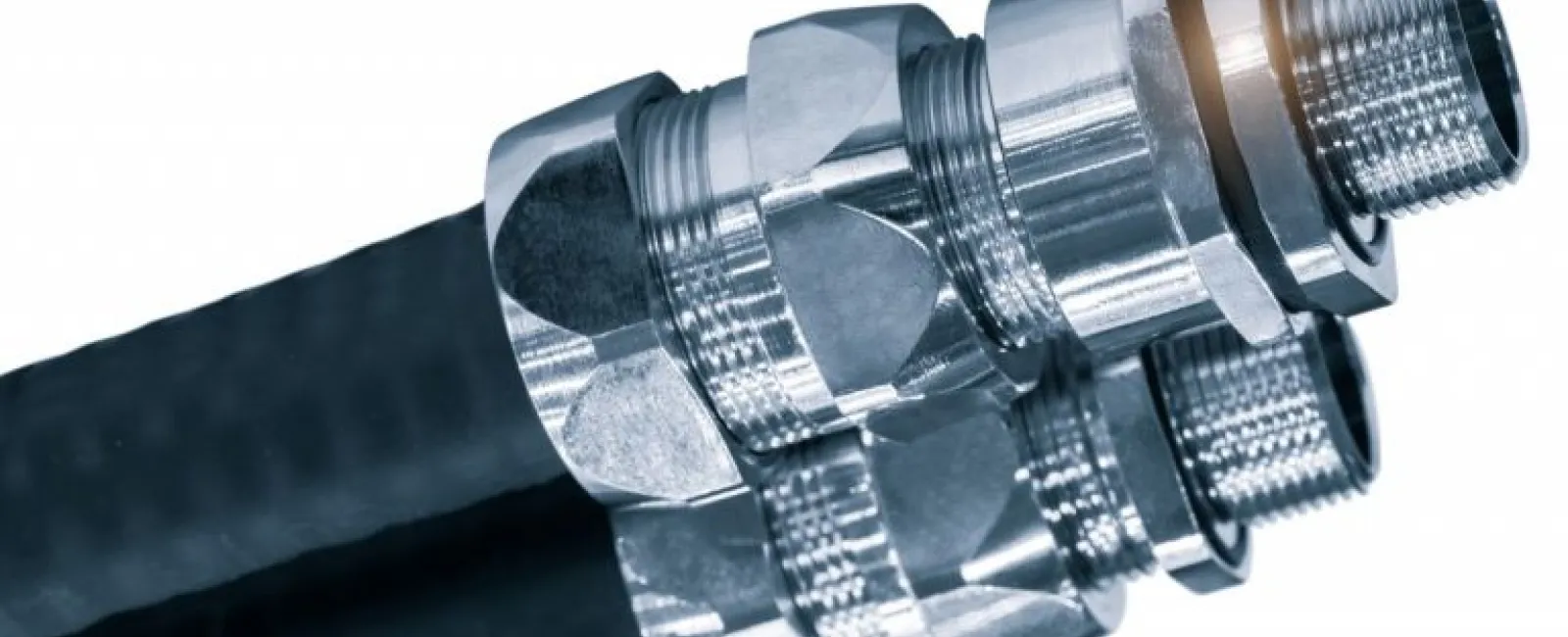 Close-up of hydraulic hoses with shiny metal connectors and threaded fittings on white background